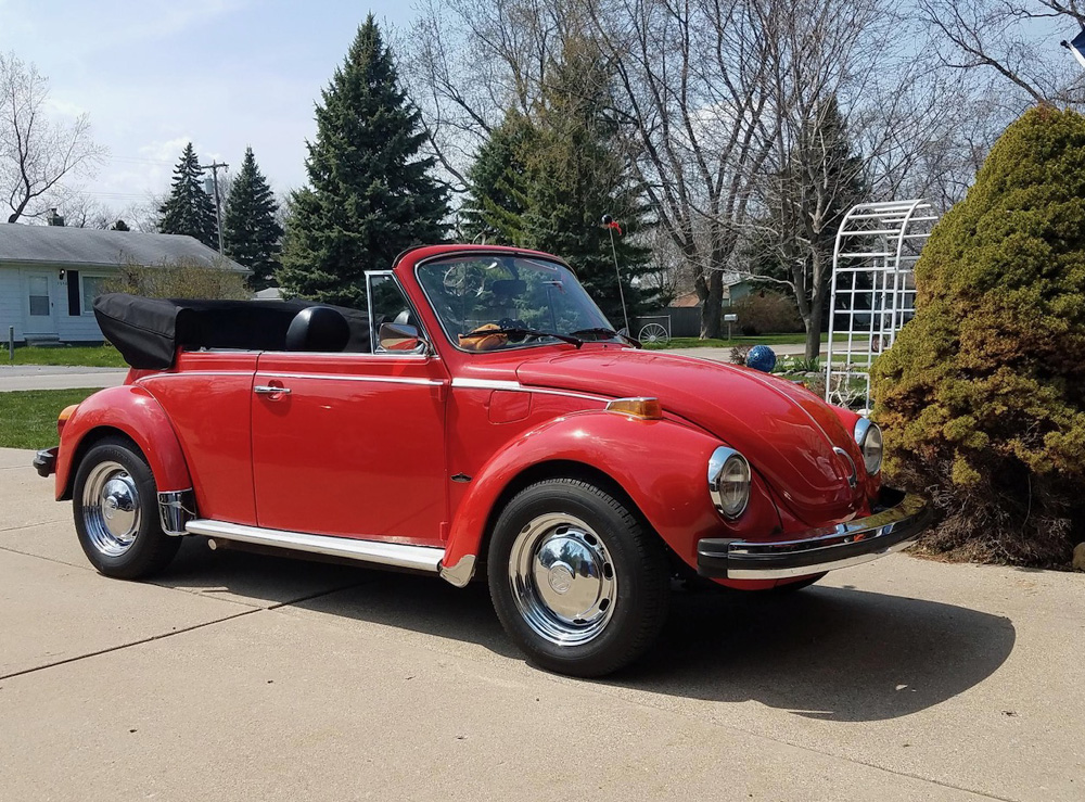 Red Super Beetle convertible on driveway