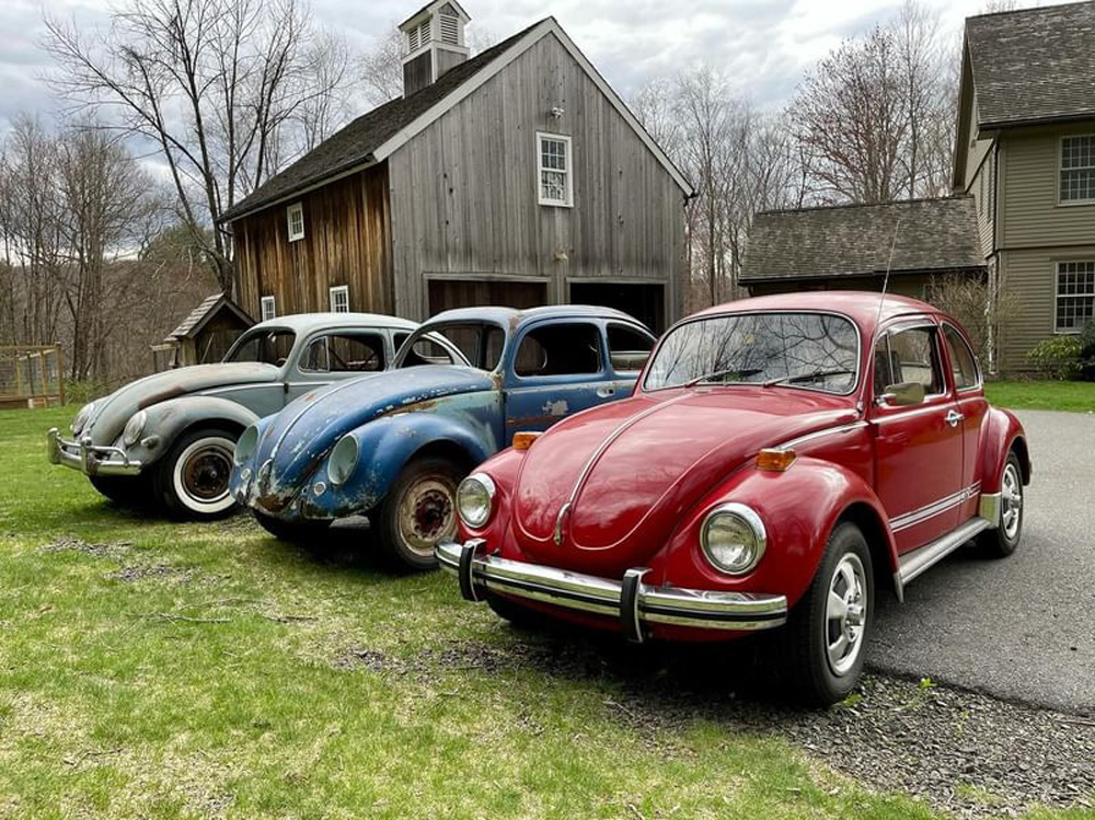Three VW Beetles in a row by a barn