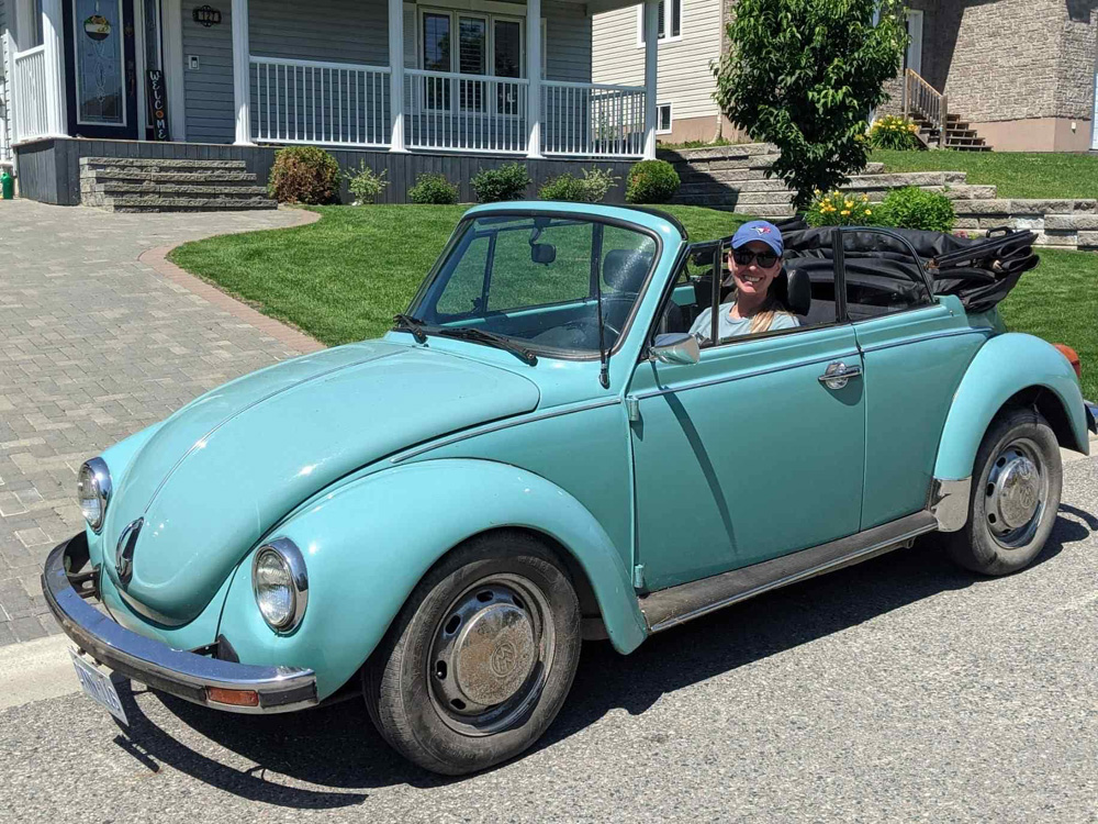Blue Super Beetle convertible with owner seated inside