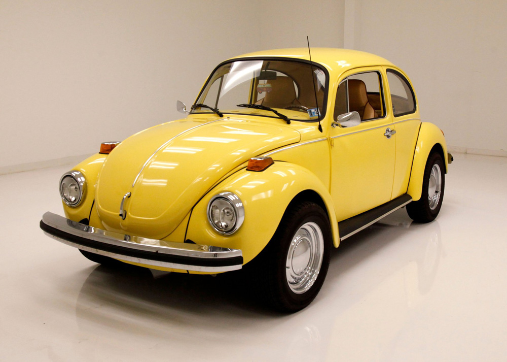 Yellow Volkswagen Super Beetle displayed indoors on a glossy white floor