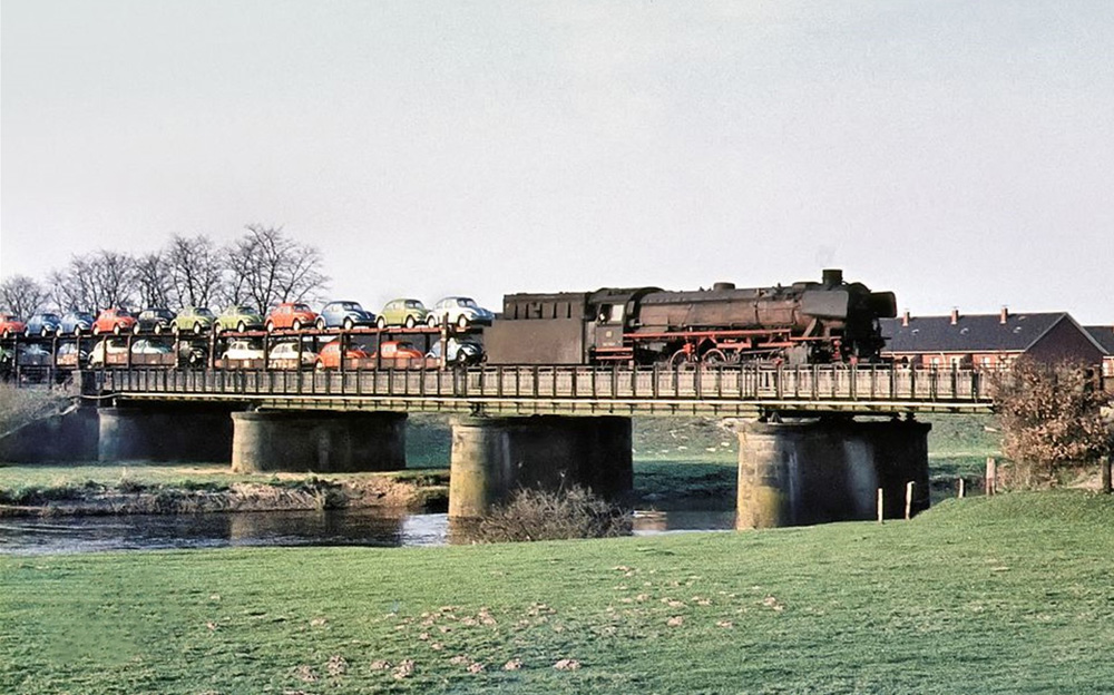 Deutsche Bundesbahn crosses the Hasebr&uuml;cke over the River Hase in Meppen, West Germany in April 1973 with a double-deck train of new Volkswagen 1303s from the Factory